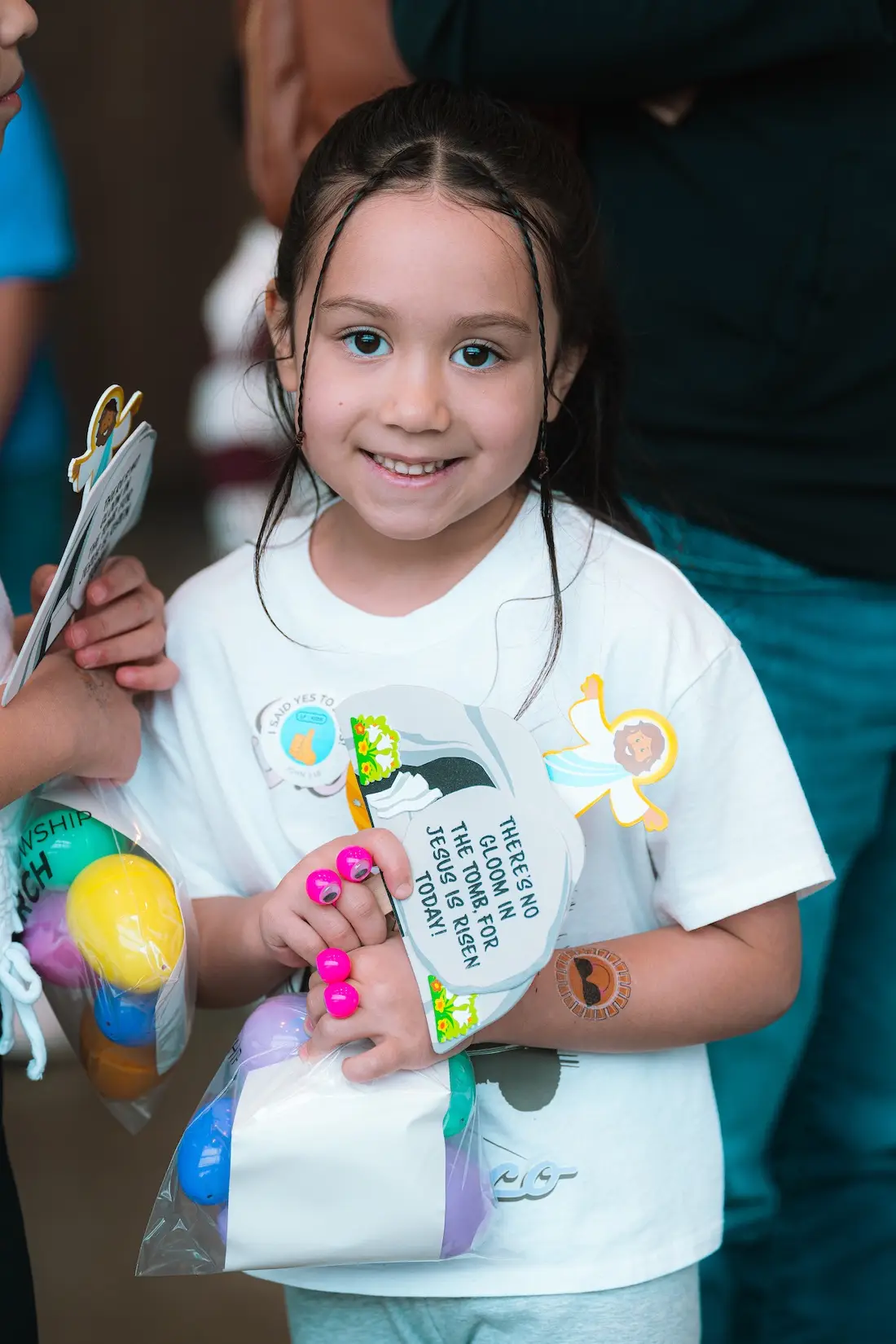 A child holding an invitation and a small ball