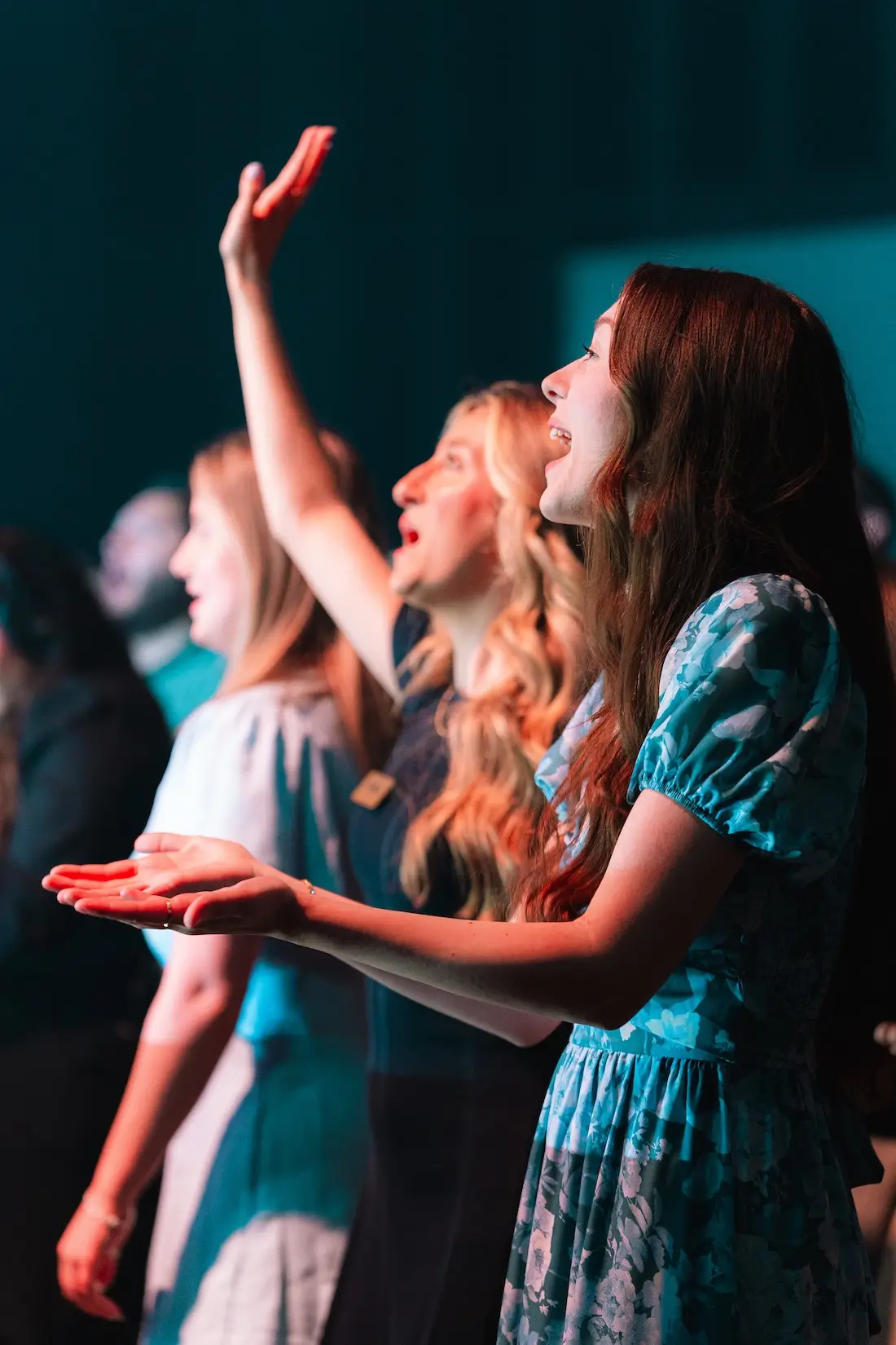 Children singing together with their hands raised