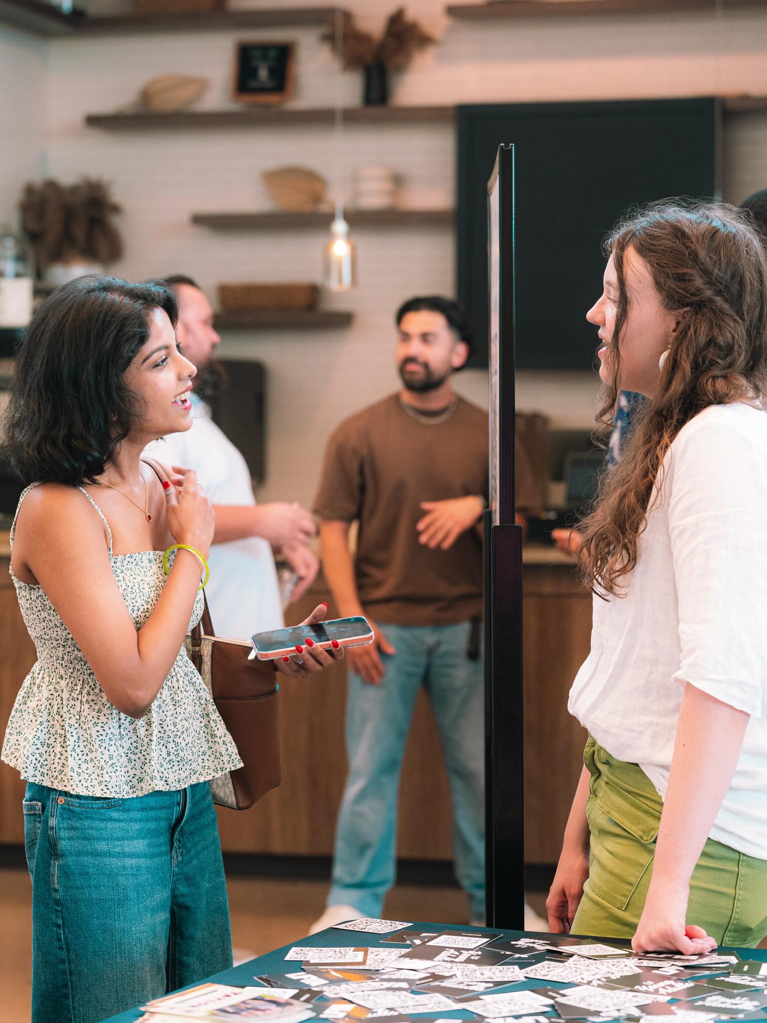 Two people talk and smile together beside an information table in the church lobby.