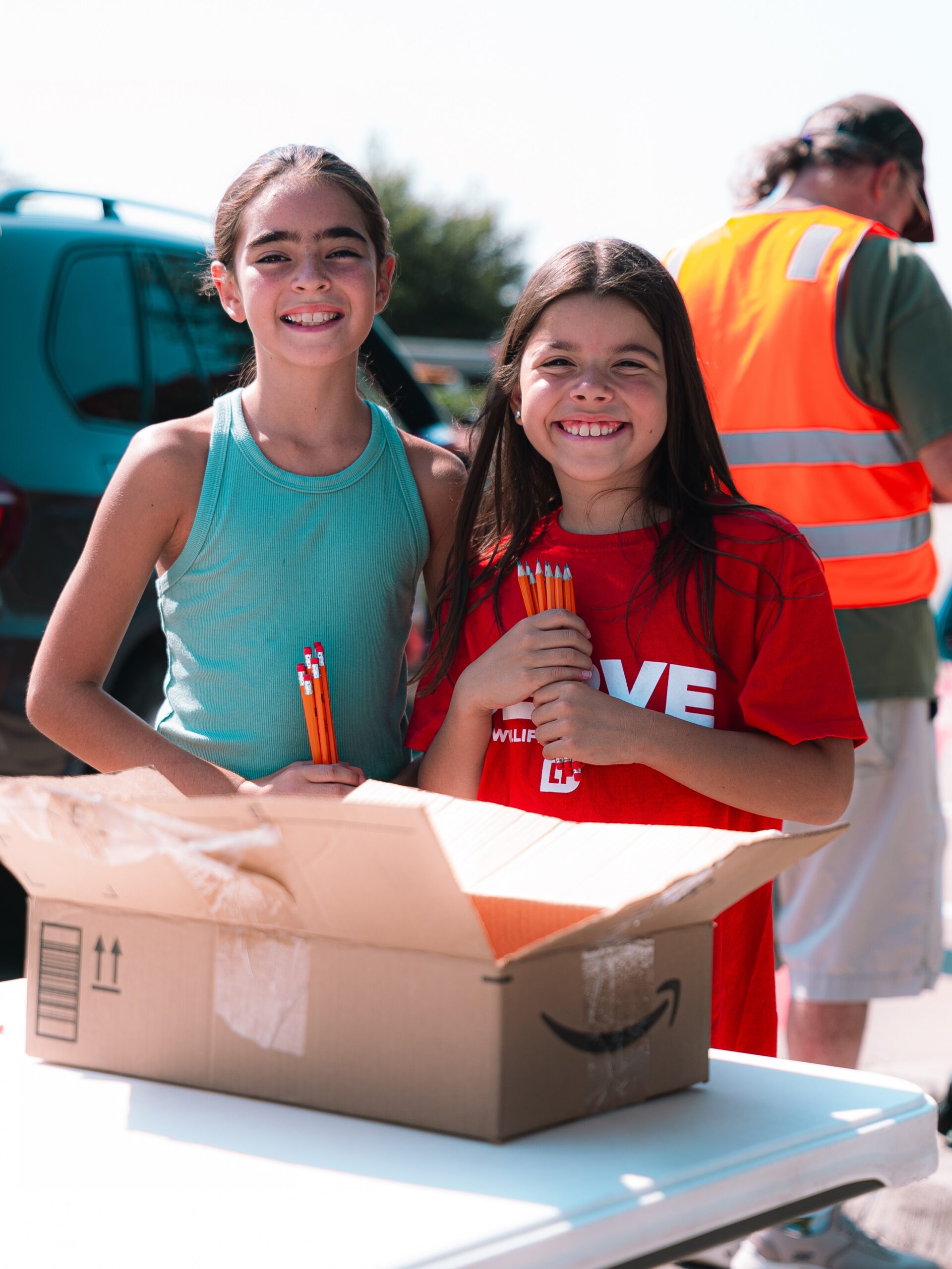 Two smiling volunteers stand behind a table of outreach supplies.