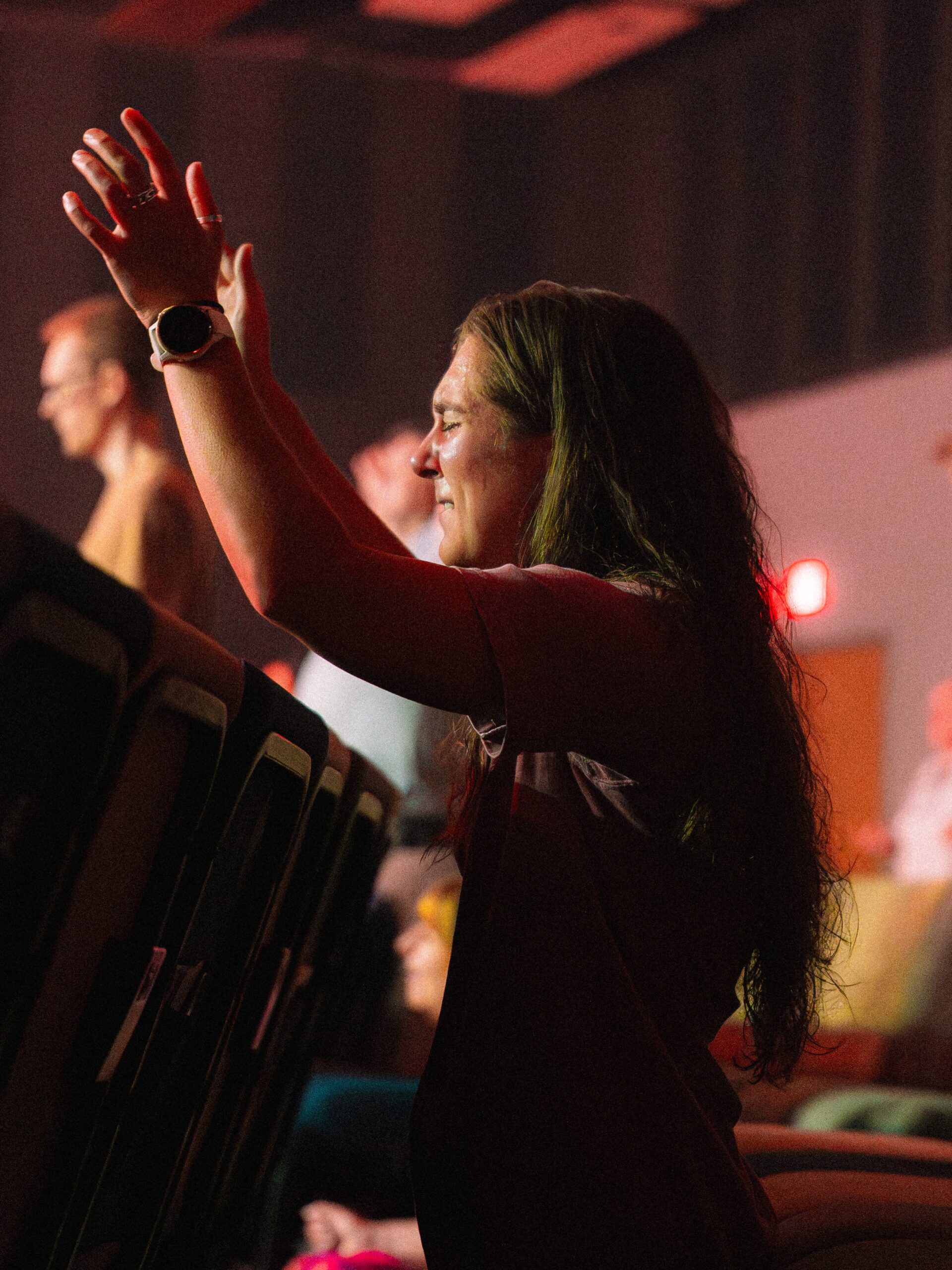 A congregation member raises her hands during a worship gathering.