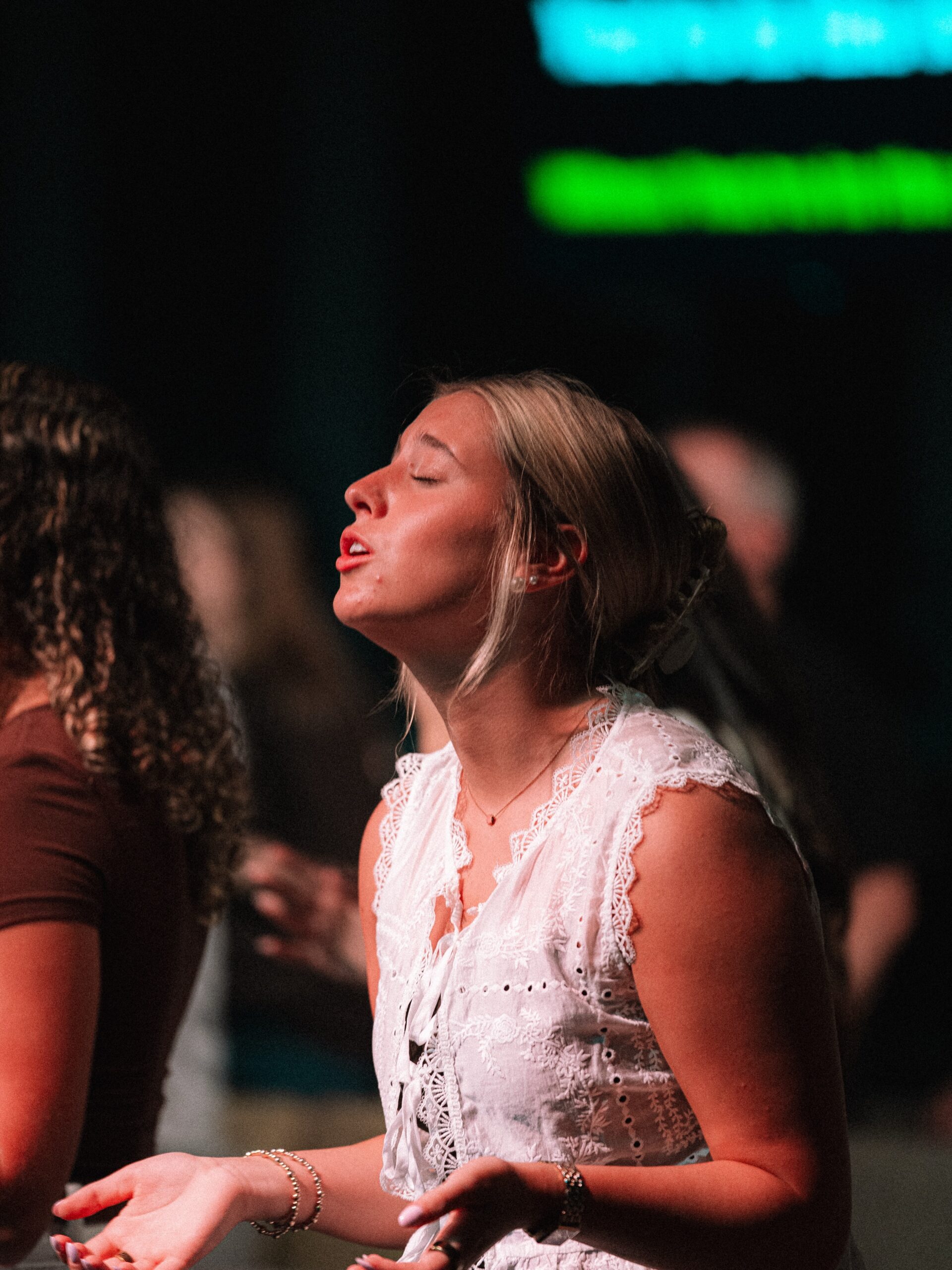 A congregation member sits with her eyes closed and hands open during worship.