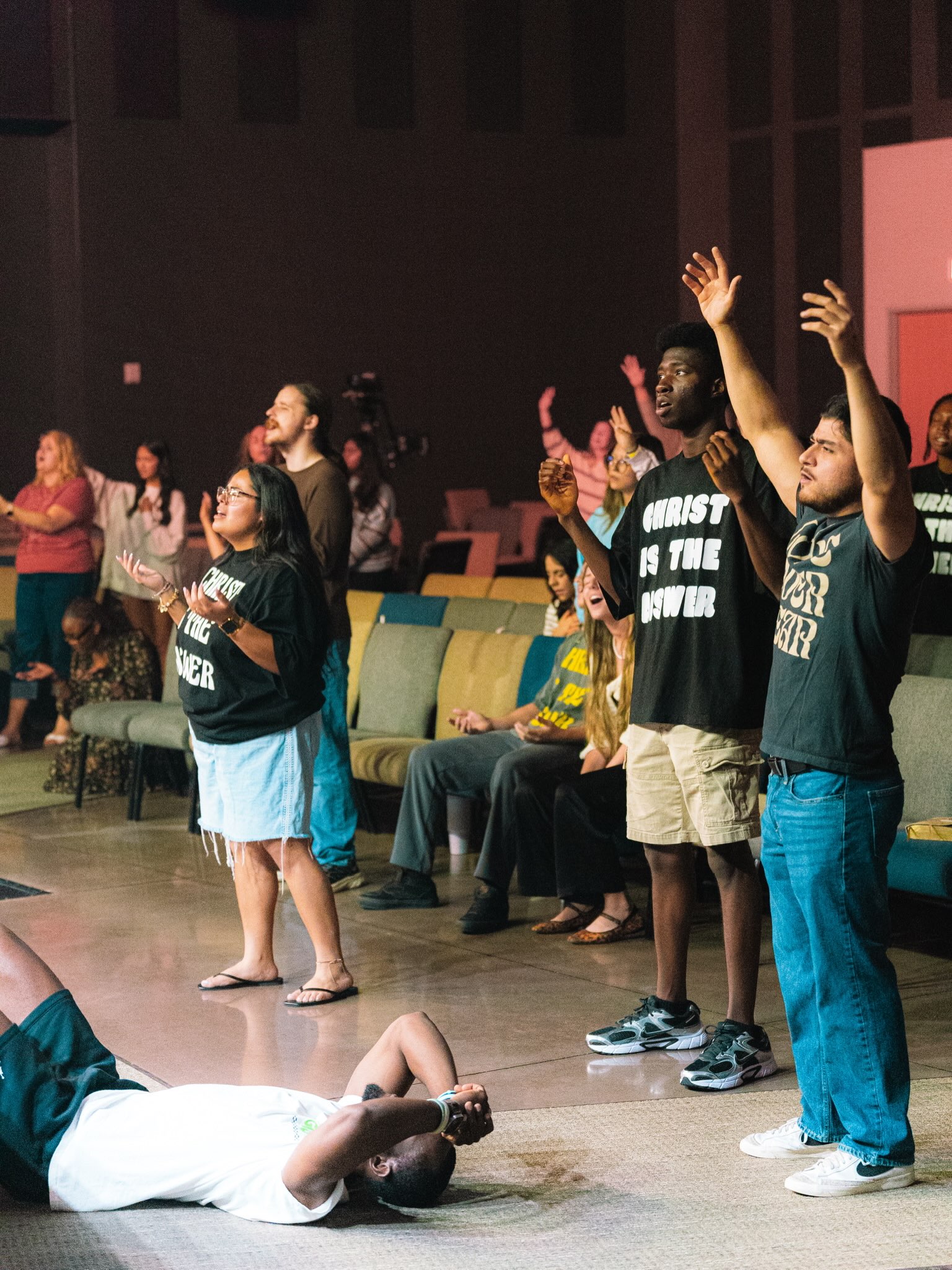 Young adults worship together with raised hands.
