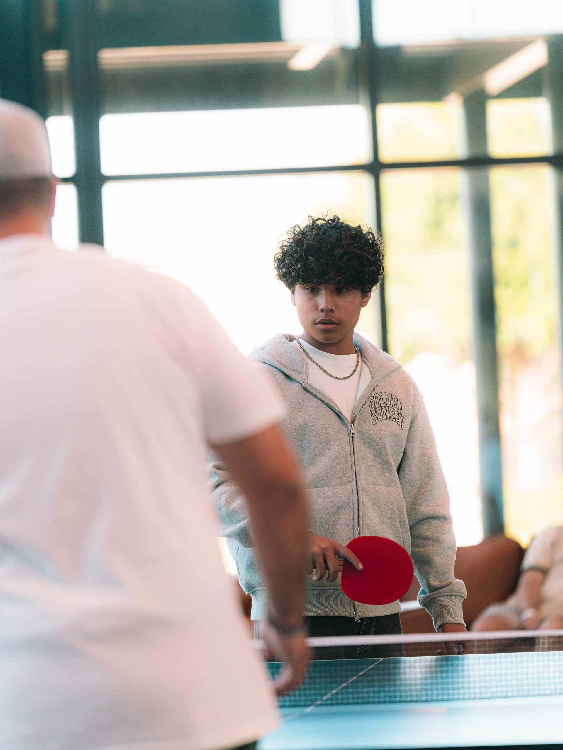 Students play table tennis together in the church lobby.