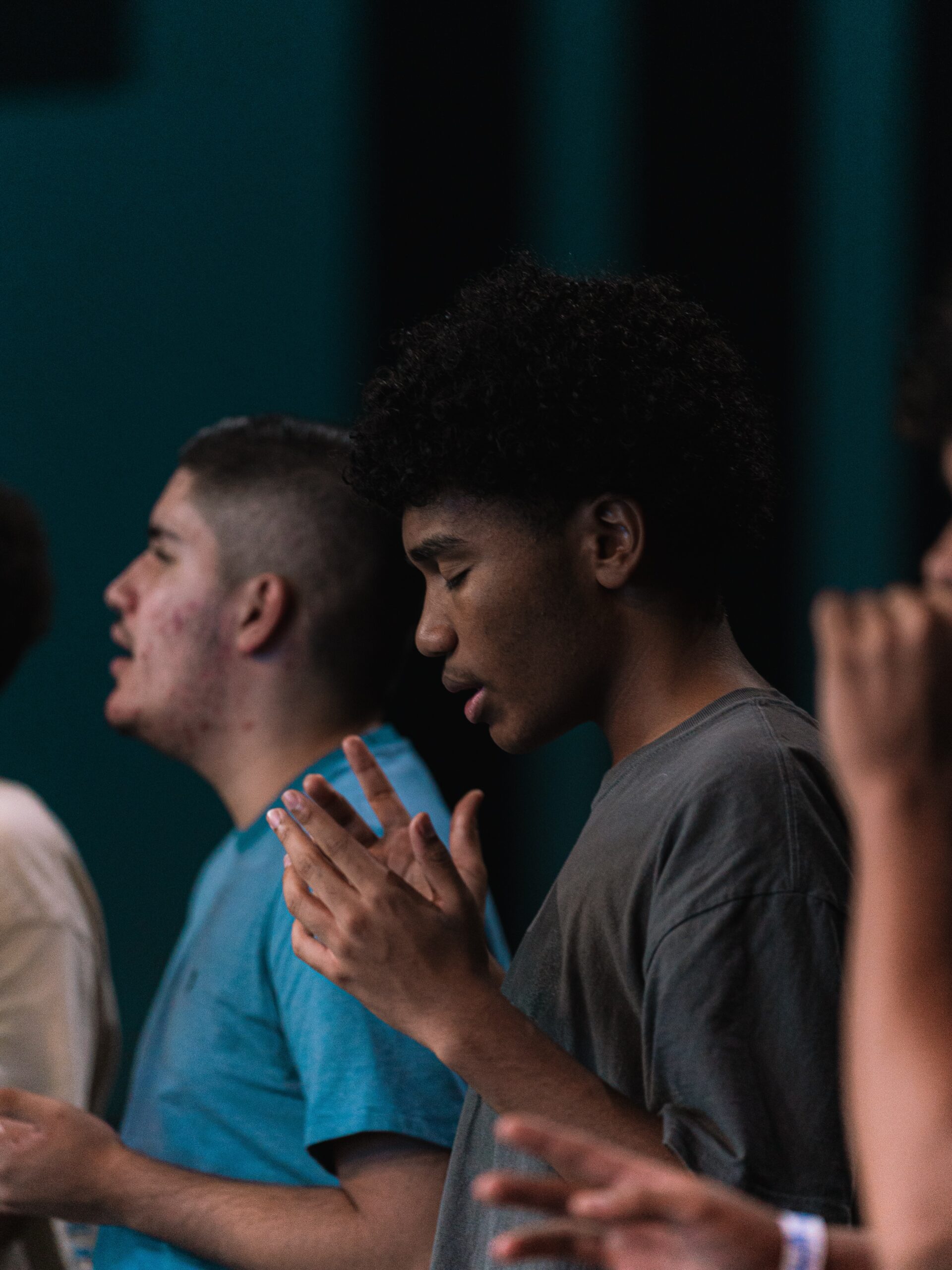 Students stand with their heads bowed and hands lifted during prayer.