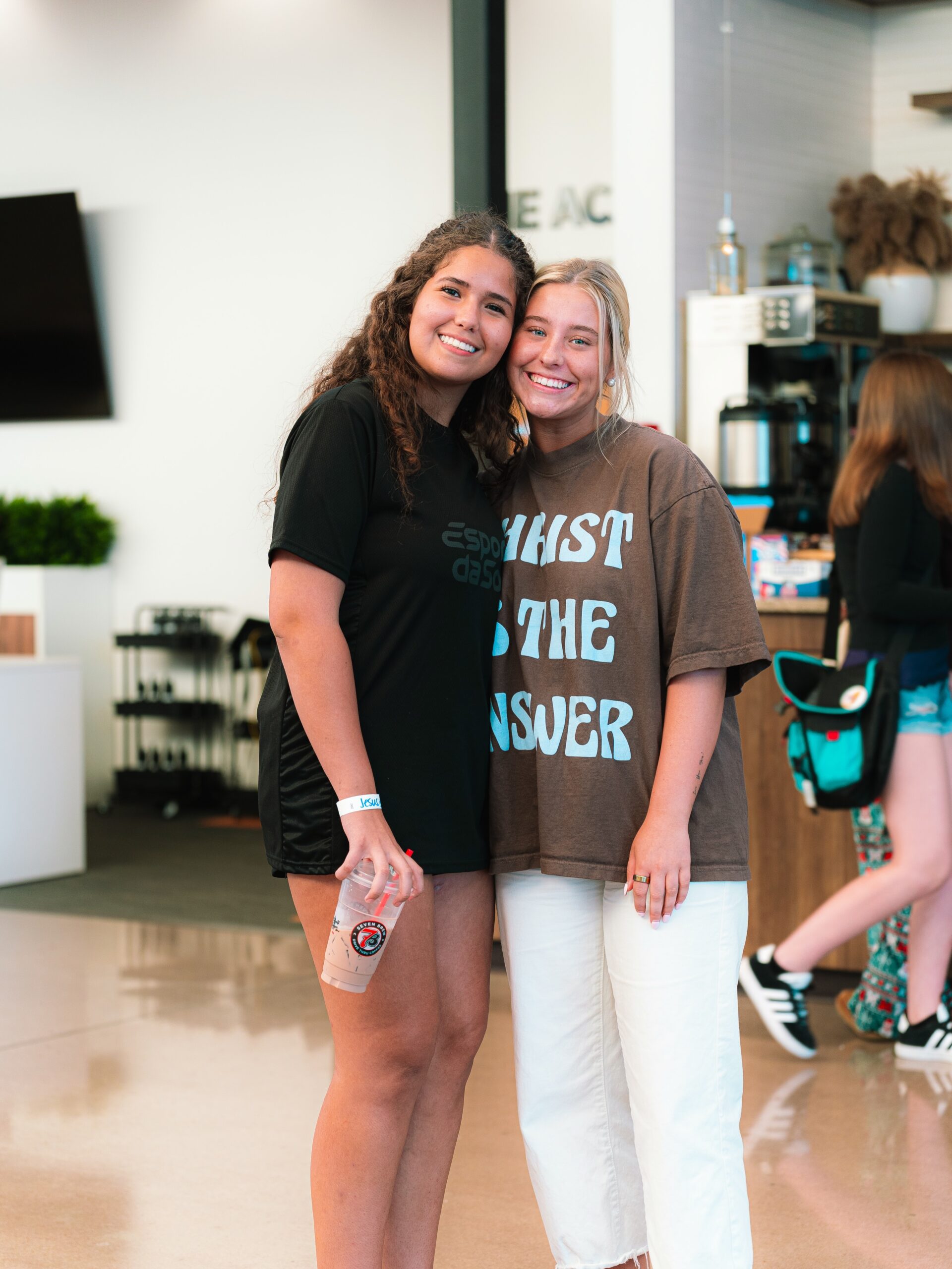 Two smiling students stand together in the church lobby.